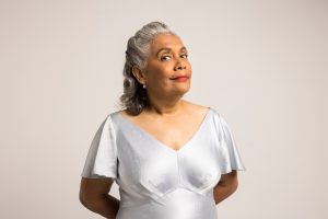 Photograph of a woman standing in a silver shirt.