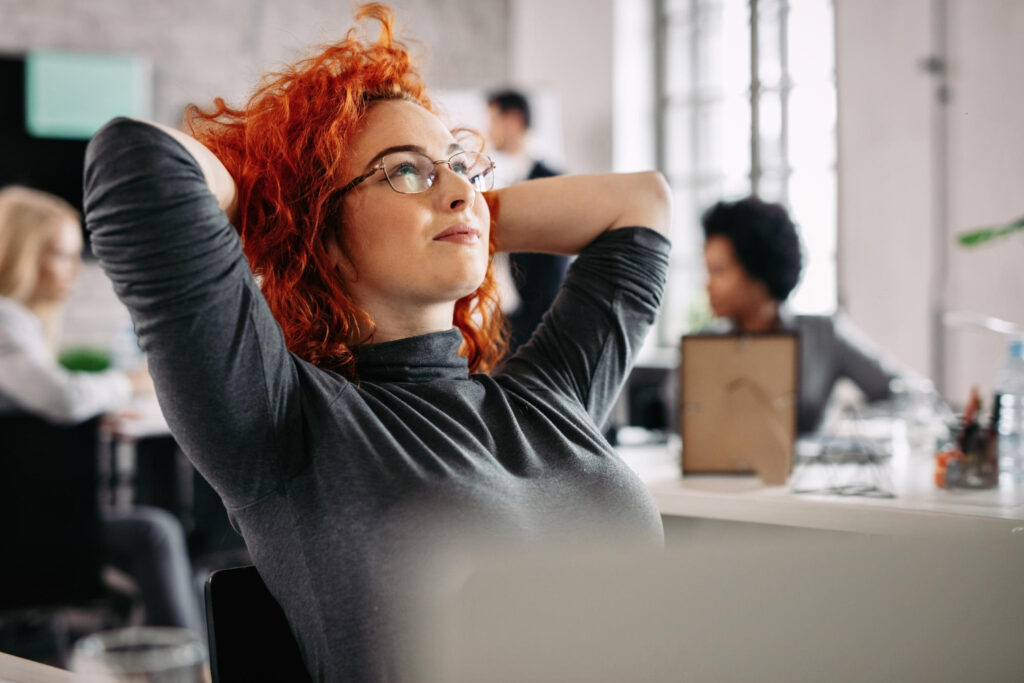 satisfied redhead businesswoman resting after work day dreaming office there are people background