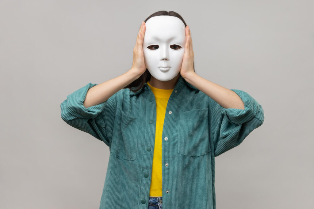 unknown woman holding white mask standing covering face multiple personality disorder