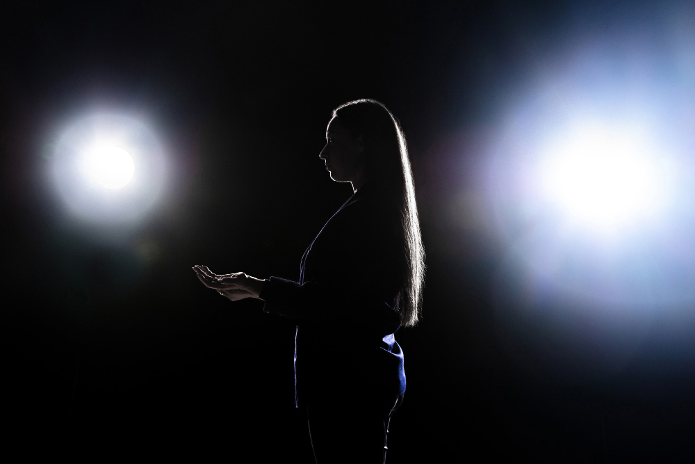 silhouette young woman gesturing isolated black wall with flashlights copyspace